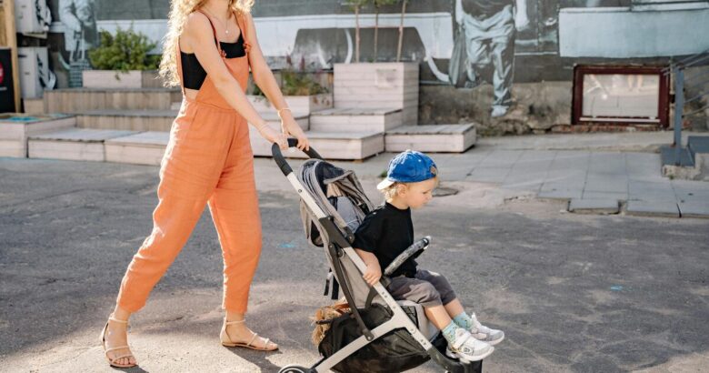 Madre paseando con su hijo pequeño en una silla de paseo ligera y compacta por la ciudad.