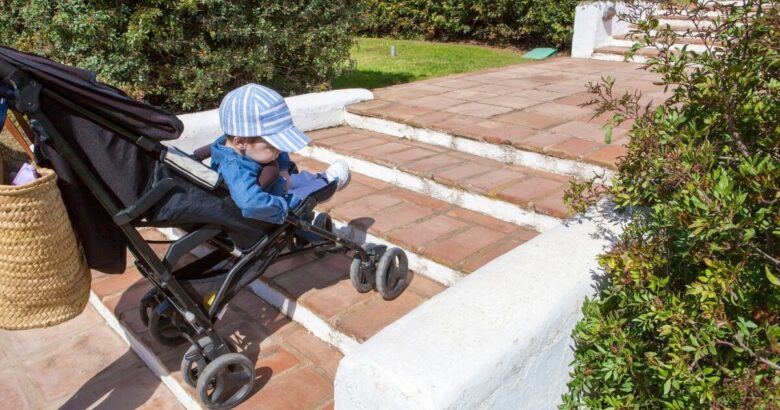 Bebé en carrito delante de unas escaleras en un edificio sin ascensor
